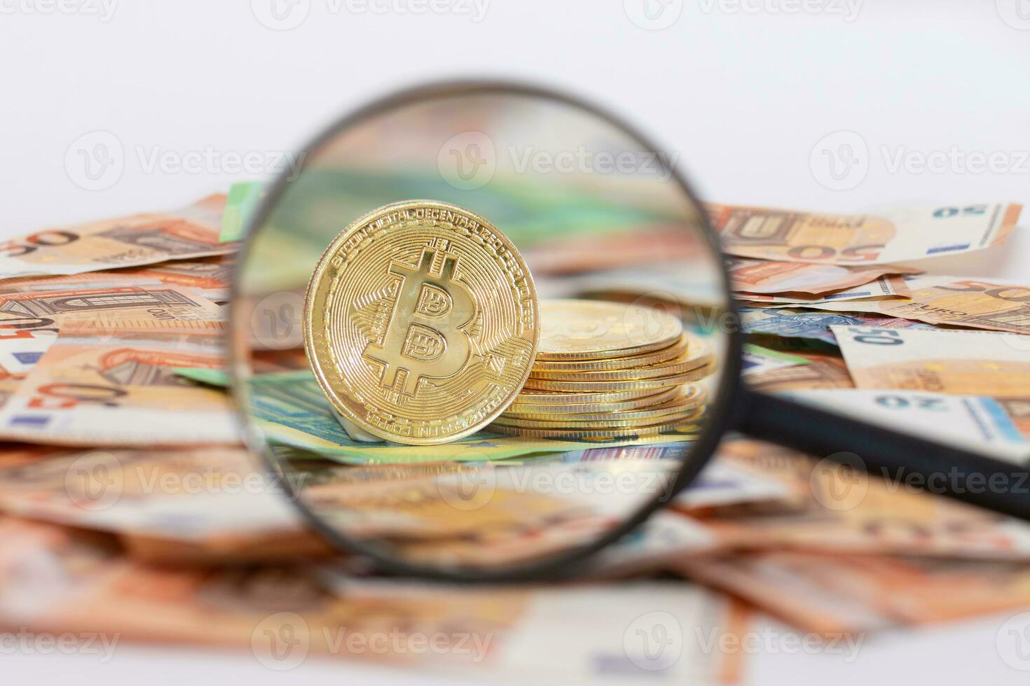 A Stack of Bitcoin Coins Visible Through a Magnifying Glass on the 50-Euro Banknotes. Euro Currency and Crypto Currency. Orange Paper Money. A Lot of Fifty-Euro Bills. Anonymous Payments Concept photo