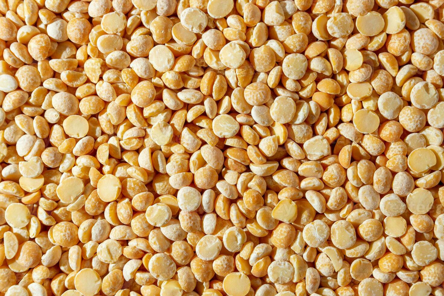 Uncooked Polished Split Peas Background. A Culinary Canvas of Dry Yellow Peas, Creating a Lively and Textured Background for Gourmet Cooking. Scattered Raw Polished Peas. Healthy Eating Ingredients photo