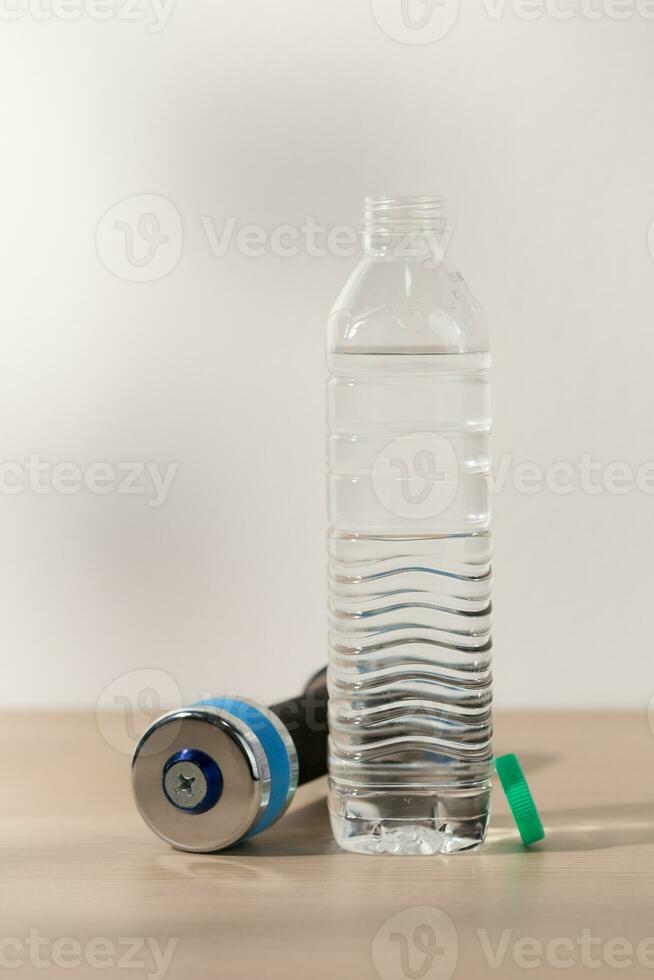 Dumbbells and drinking water in a plastic water bottle. photo