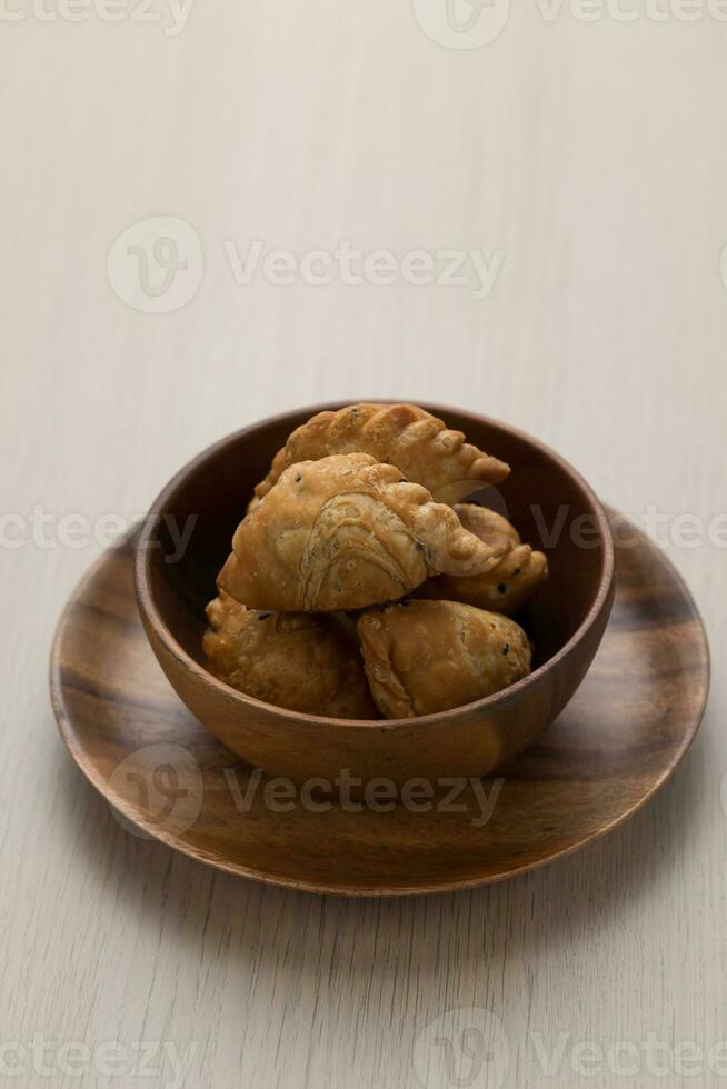 Thai-style curry puff in a dark brown wooden bowl. photo