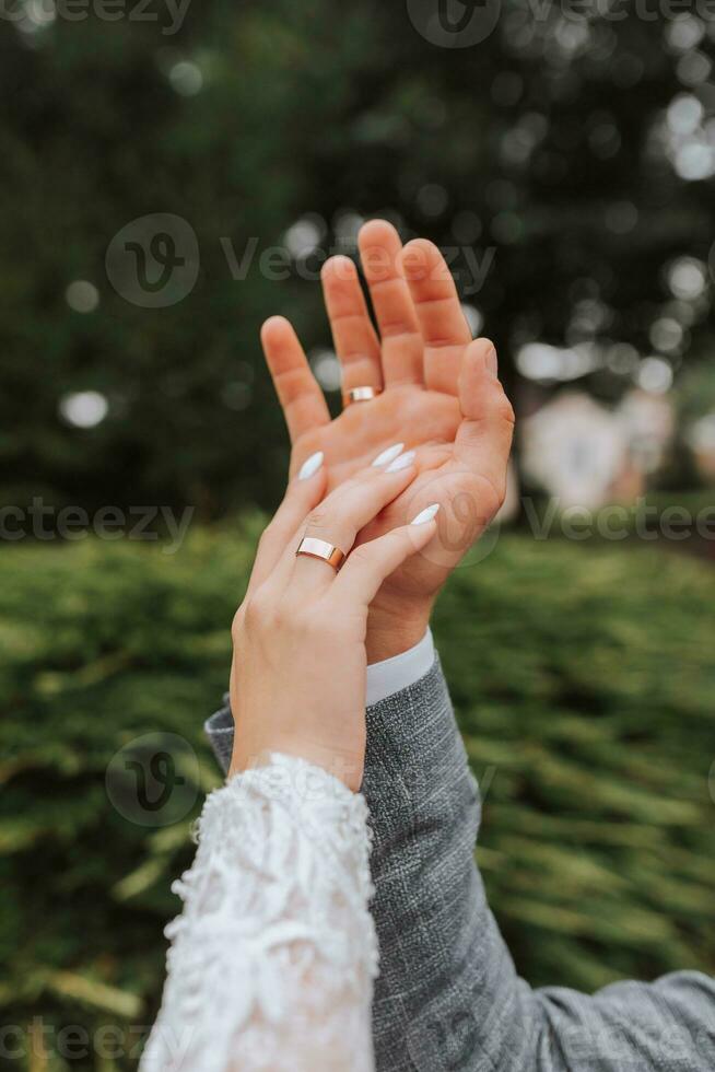 A beautiful luxury wedding. Close-up of bride and groom's hands. The groom holds the bride's hand. Gentle touches of fingers. Wedding ring photo