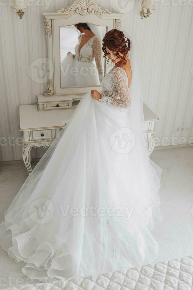 The bride in a beautiful dress holds the train of the dress in her hands. Wedding. wedding bouquet Morning of the bride. A happy bride is waiting for the groom. photo