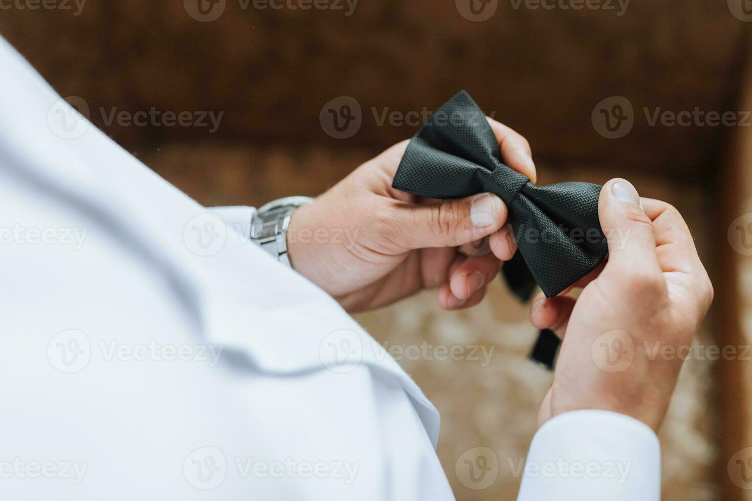 Mañana de el novio y detalles, blanco camisa, bueno luz, joven hombre, elegante novio consiguiendo vestido, consiguiendo Listo para el Boda ceremonia. de cerca de masculino manos, masculino mariposa en manos foto