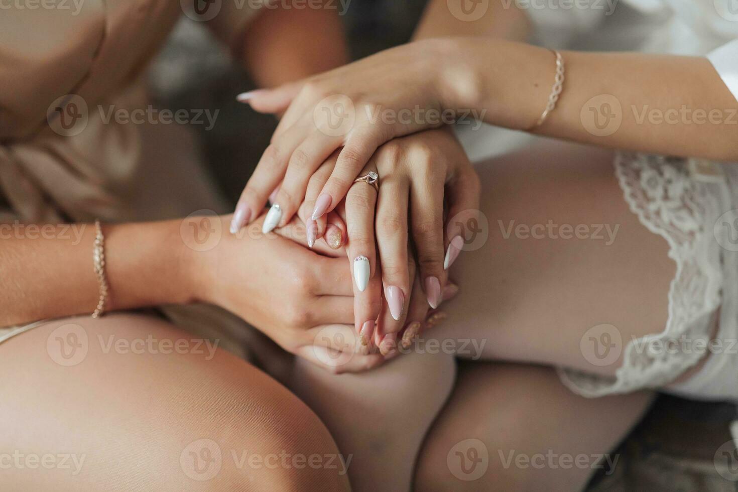 Photo of wedding details. Beautiful hands of the bride and her friend. Gorgeous jewelry on hands. French manicure. Wedding photo in a light tone. Cropped photo. Morning of the bride.