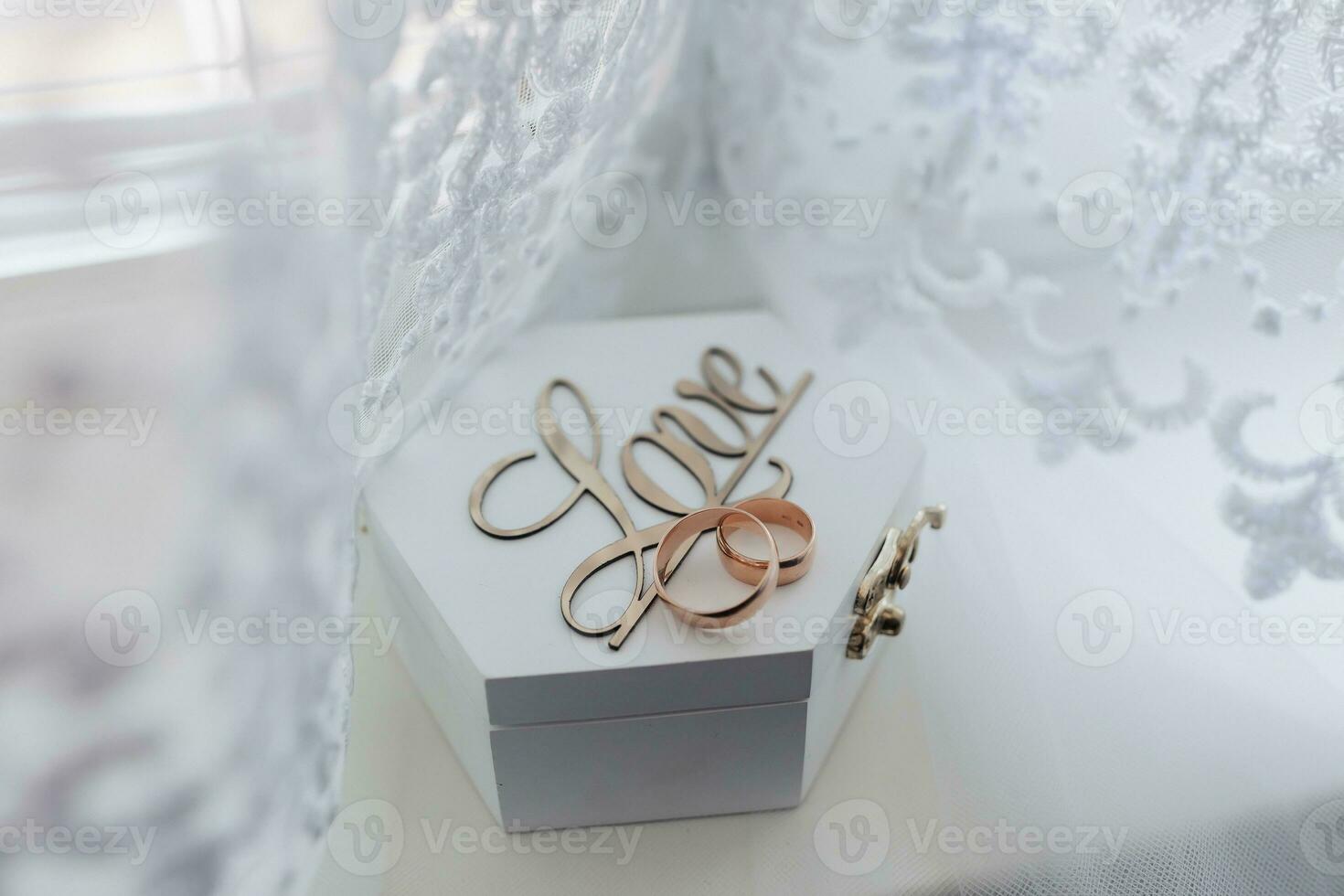Wedding rings stand on a wooden box on a white background. The inscription love on a box for wedding rings. Wedding details. photo