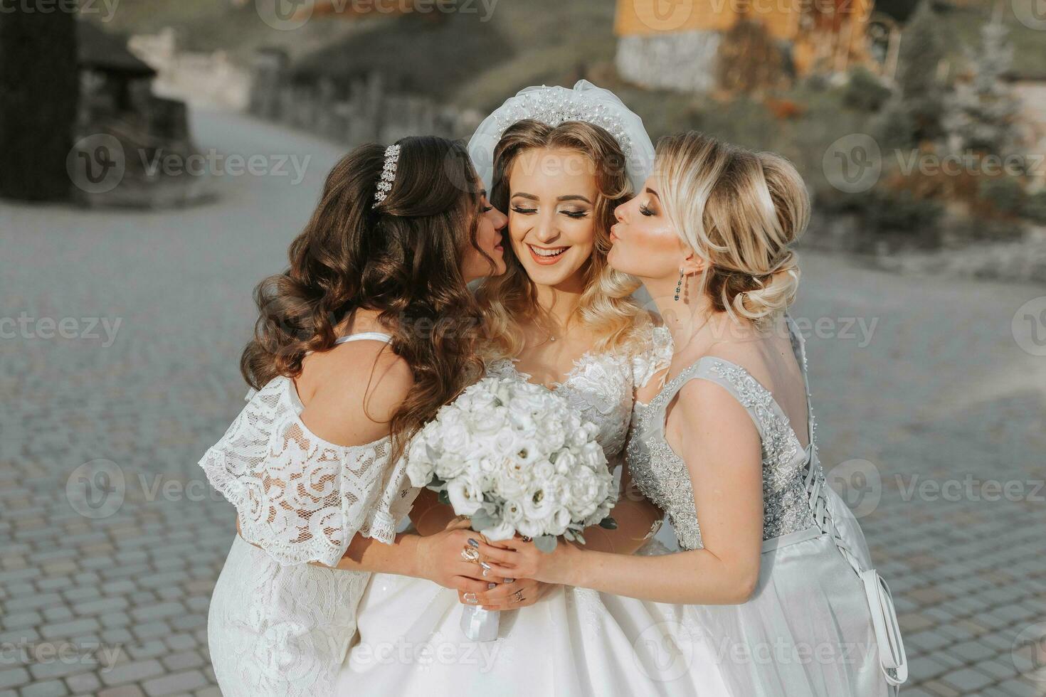 Stylish bridesmaids have fun with the bride in nature and pose and kiss the bride photo