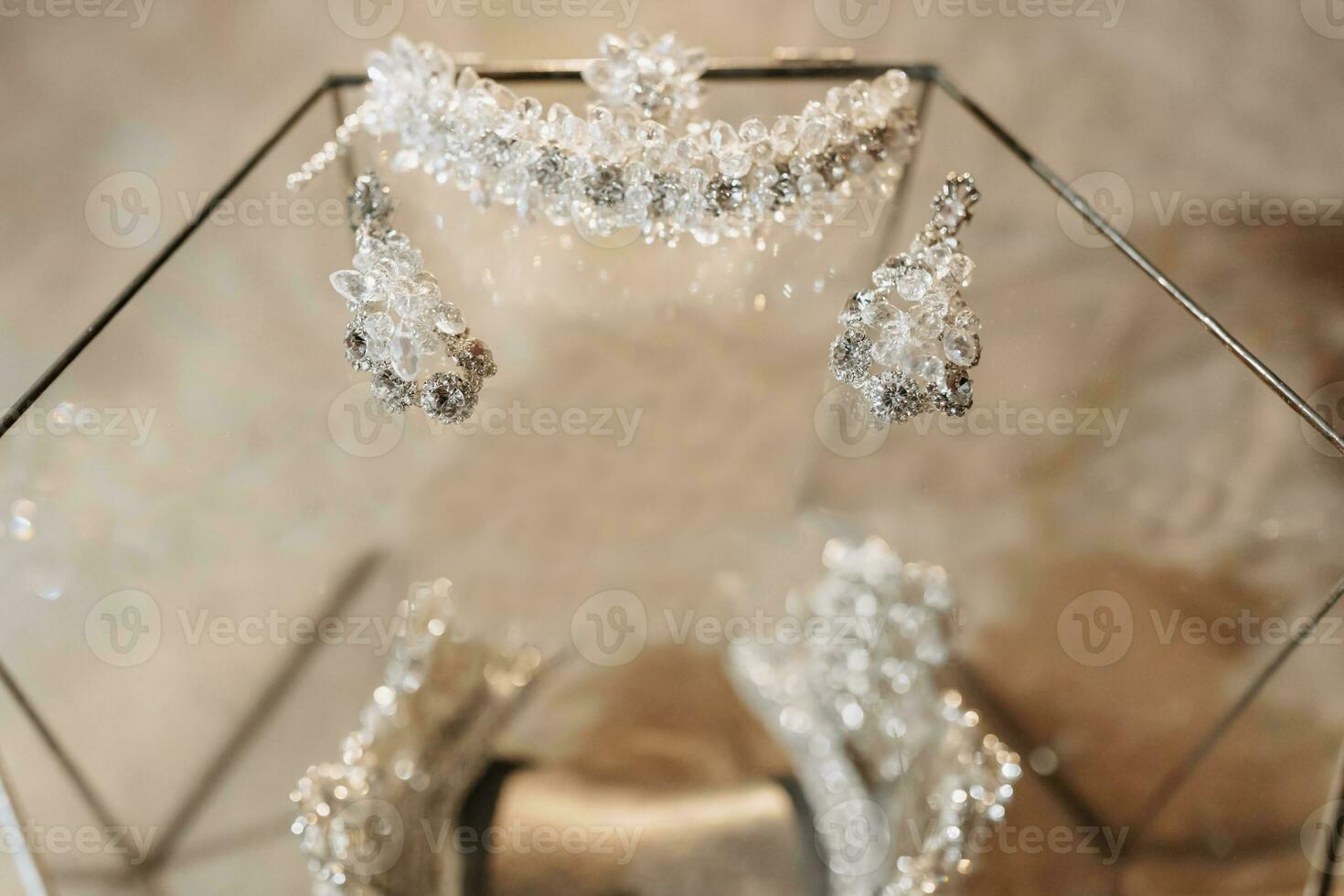 Wedding crown tiara in a glass box on the bed, bracelet on the hand of the bride and royal earrings. Luxury accessories photo