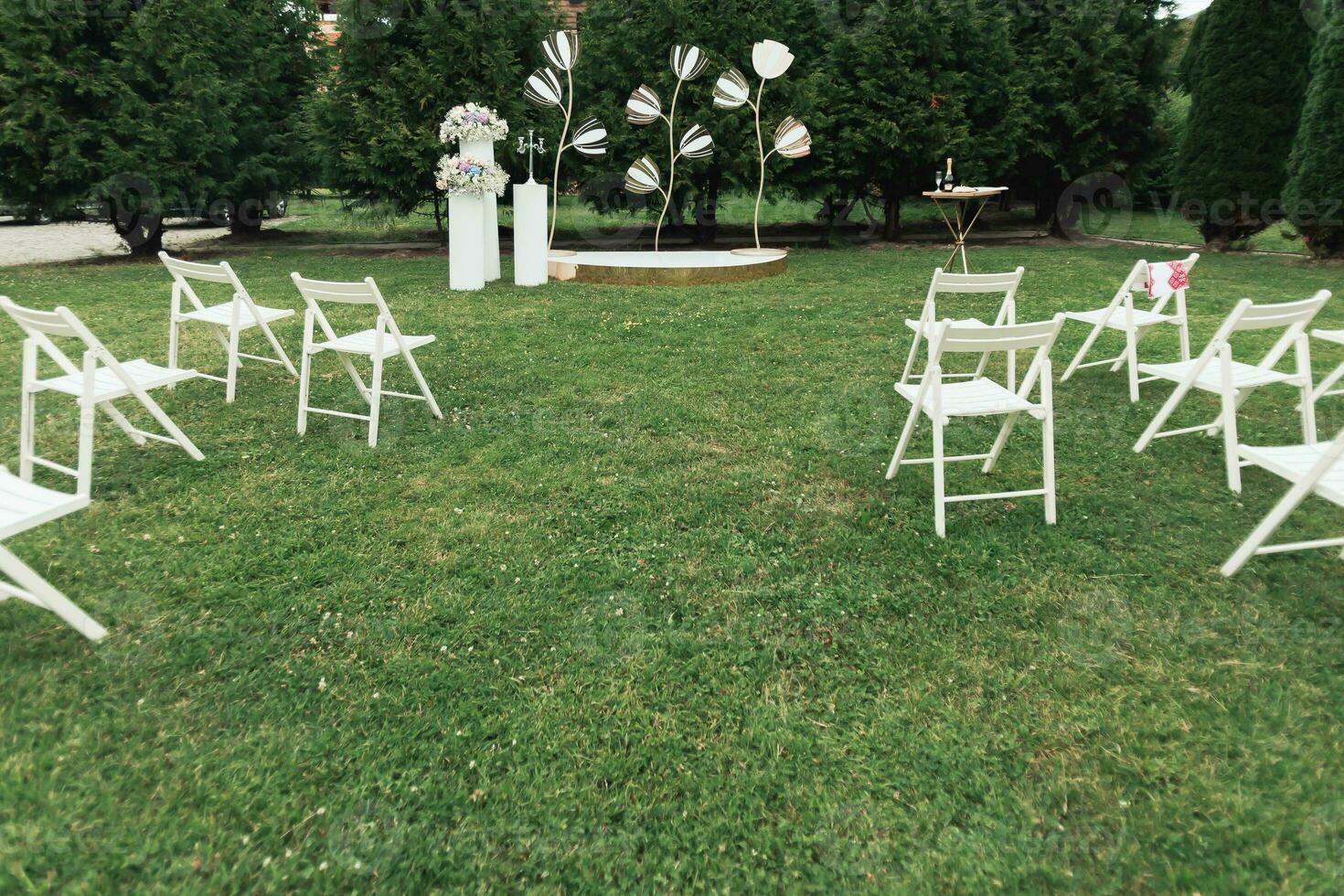 wedding ceremony in the garden. A luxurious wedding ceremony. Romantic wedding ceremony. The stands are decorated with colorful flowers. White chairs photo
