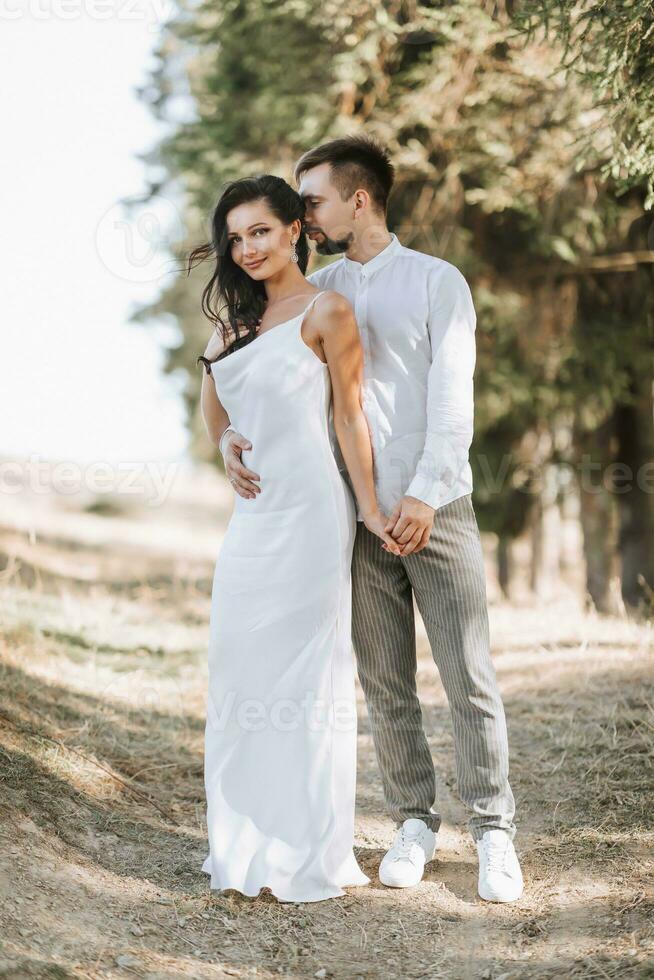 Young happy couple in love hugging smiling and having fun in the mountains. High quality photo. A girl in a beautiful white dress. Portrait photo