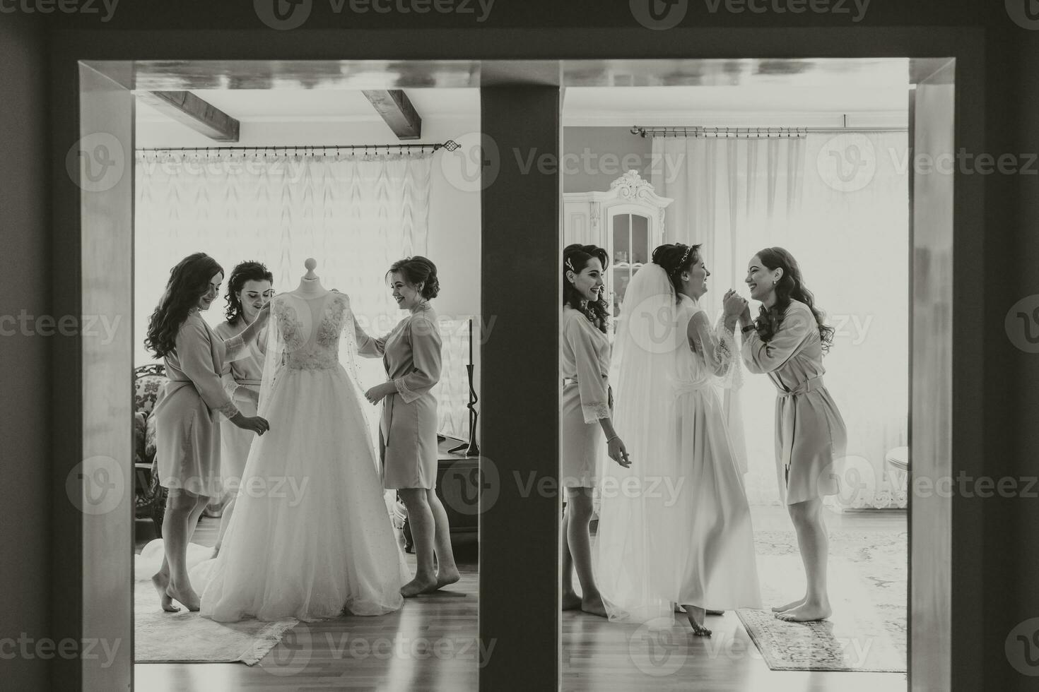 bride's girlfriend prepares the bride for her wedding day. The bride's girlfriend helps secure the bride's wedding dress before the ceremony. black and white photo