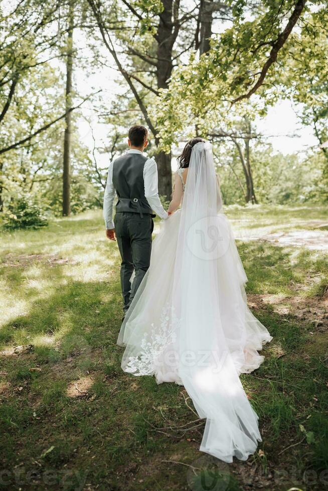 Stylish young brides, happy on their day, enjoy each other. They are walking in the spring park. Photo from the back. Spring wedding. Natural makeup