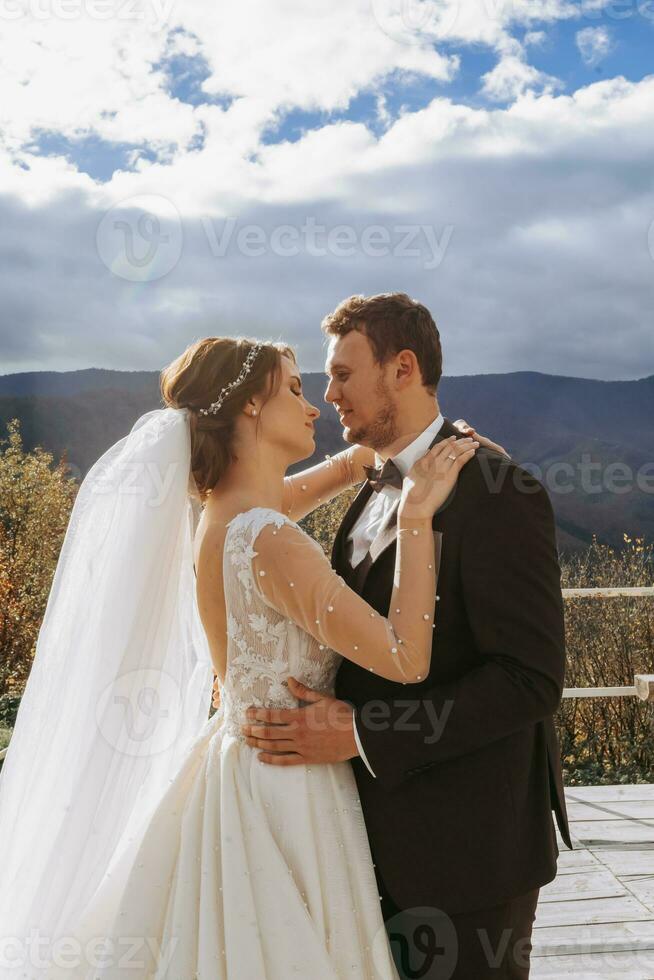 Beautiful newlyweds couple hugging in mountains at sunset. Bride and groom walking in summer Carpathians. photo