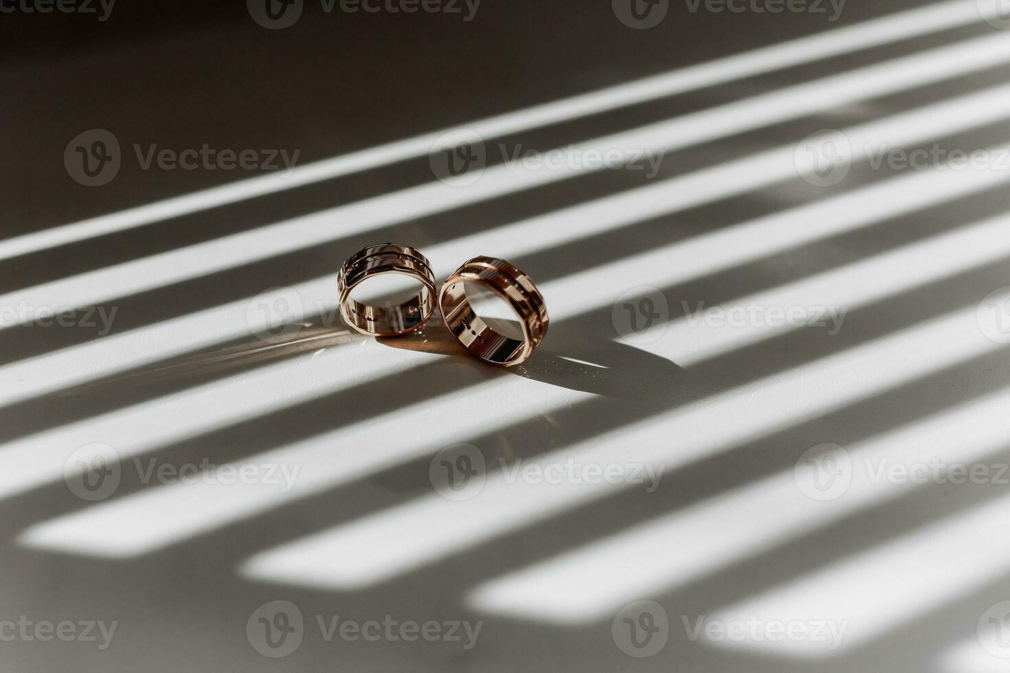 Two golden textured wedding rings on rays of falling light photo