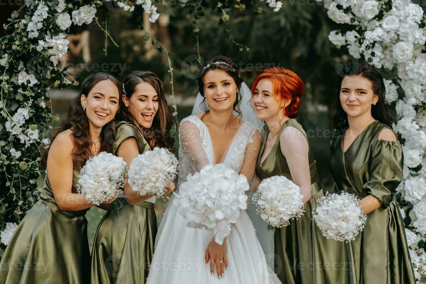 Bridesmaids smiling together with the bride. The bride and her fun friends celebrate the wedding after the ceremony in matching dresses. Bride and friends in nature photo