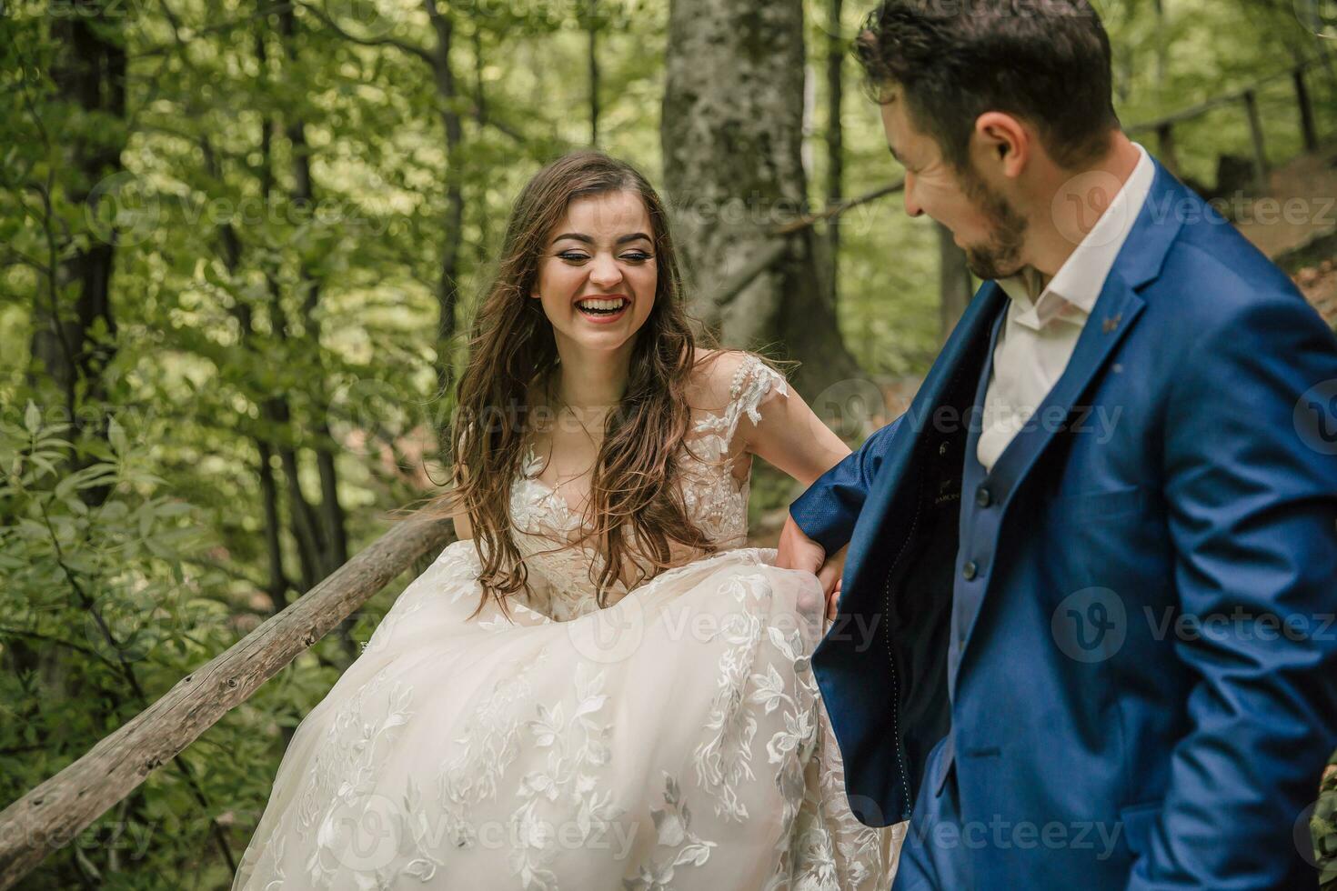 A happy wedding couple is running along a forest path. The bride smiles sincerely. Wedding photo session in nature. Photo session in the forest of the bride and groom.
