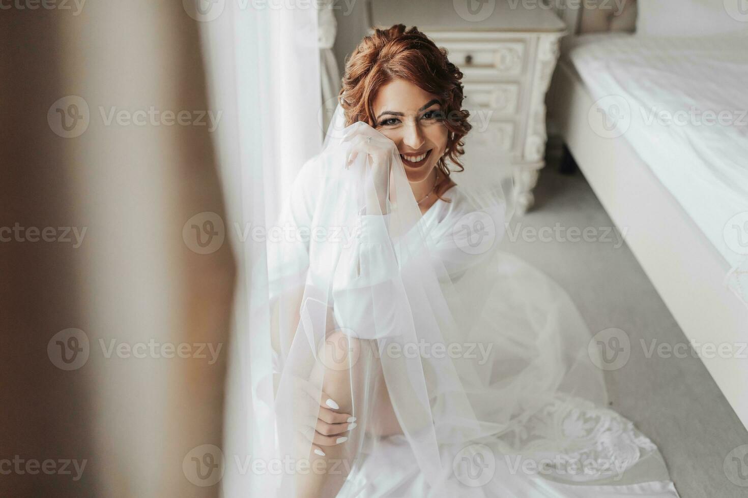 Fashion shot, beautiful woman in a dressing gown. Fashion, glamor concept. The morning of the bride, the bride in a dressing gown sits by the window posing for the photographer photo