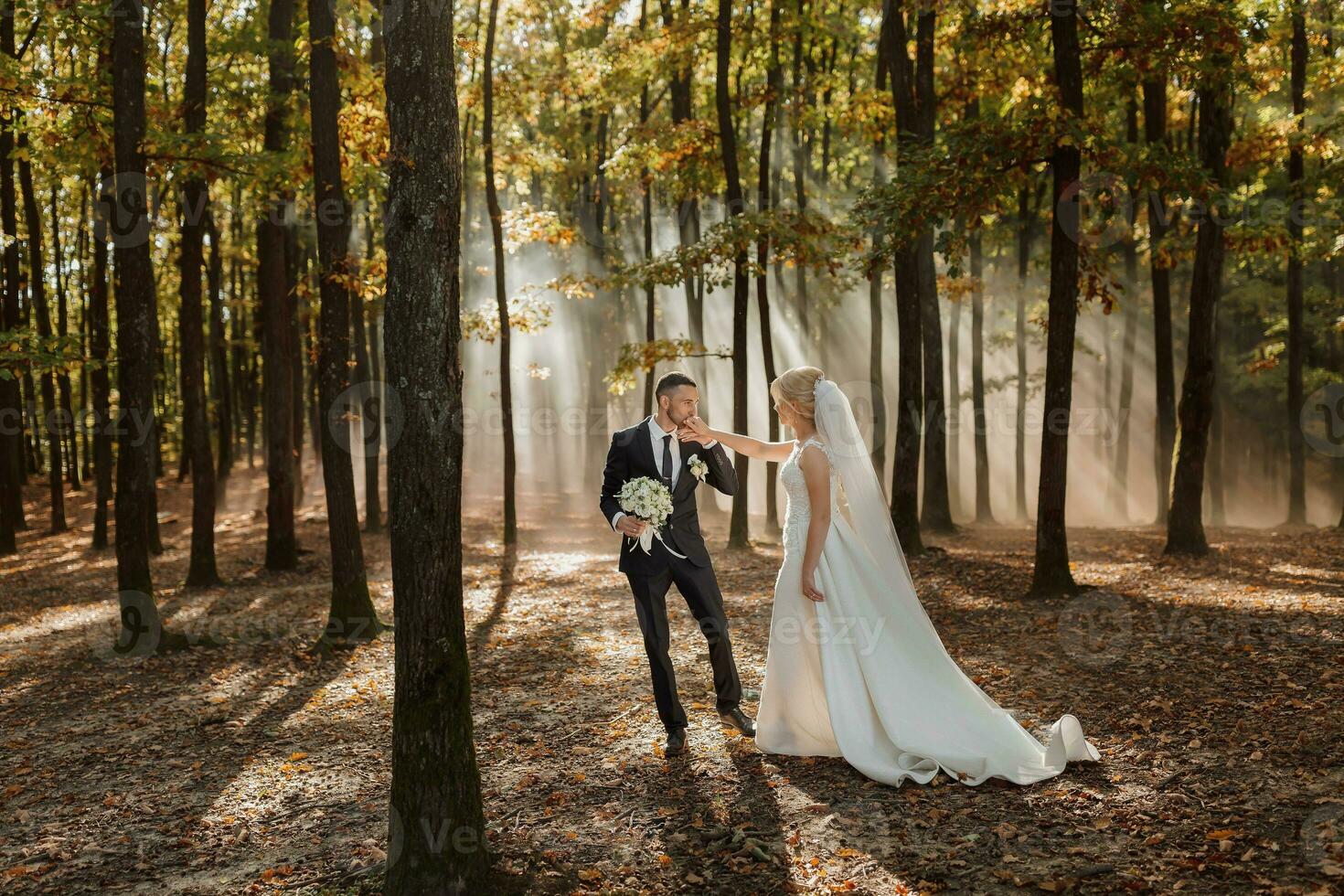 the bride and groom are dancing against the background of a fairy-tale fog in the forest. The rays of the sun break through the smoke, a fairy-tale wedding photo