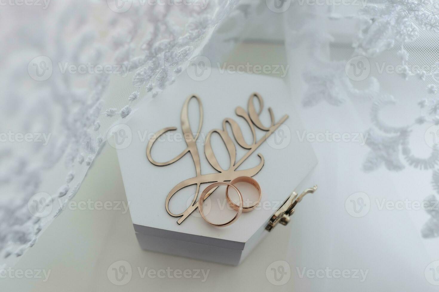 Wedding rings stand on a wooden box on a white background. The inscription love on a box for wedding rings. Wedding details. photo