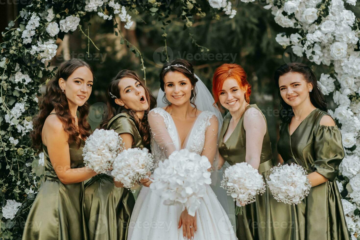 Bridesmaids smiling together with the bride. The bride and her fun friends celebrate the wedding after the ceremony in matching dresses. Bride and friends in nature photo