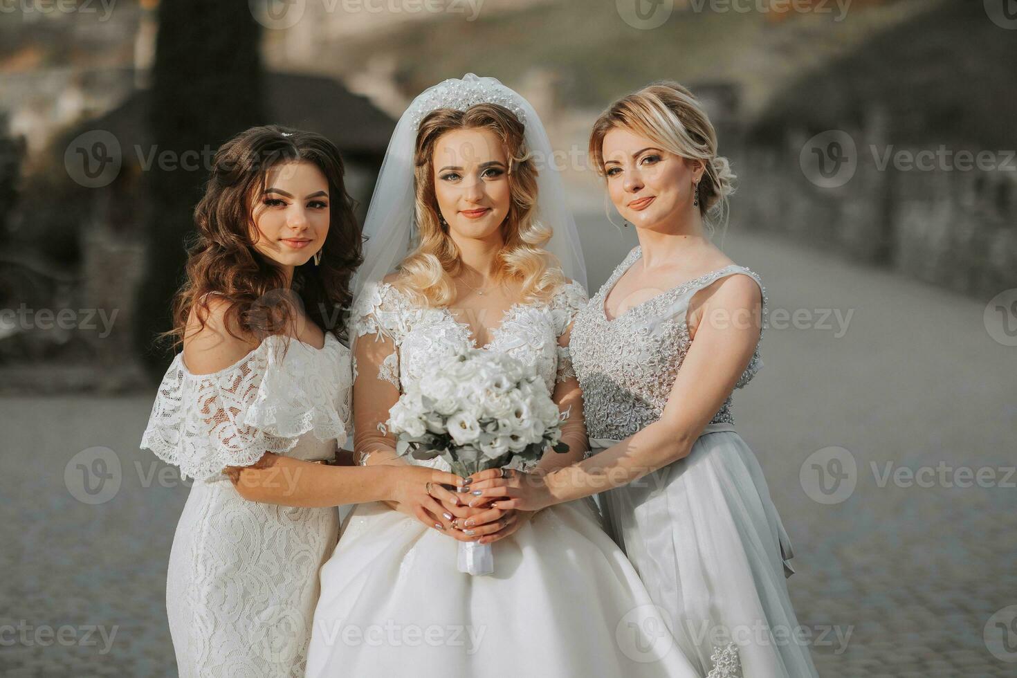 Stylish bridesmaids have fun with the bride in nature and pose looking into the camera photo