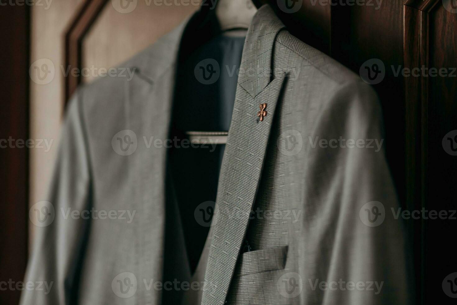 A gray stylish jacket hangs on a brown background. Men's style. Clothes. Fashion and business. Details photo