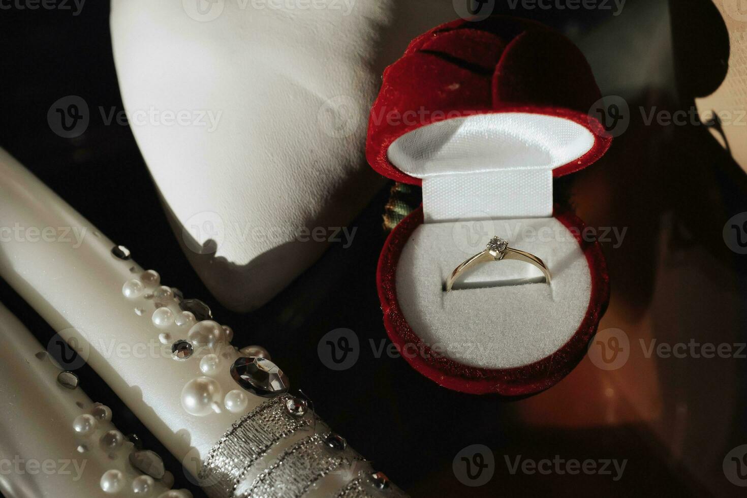 The bride's silver engagement ring with precious stones, white shoes and candles decorated with pearls. Photo of wedding details.