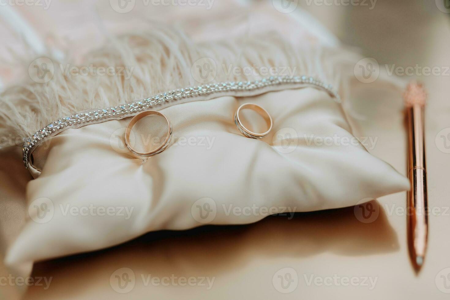 Wedding gold rings stand on a beige pillow decorated with feathers. Wedding accessories. Preparation for the wedding ceremony photo