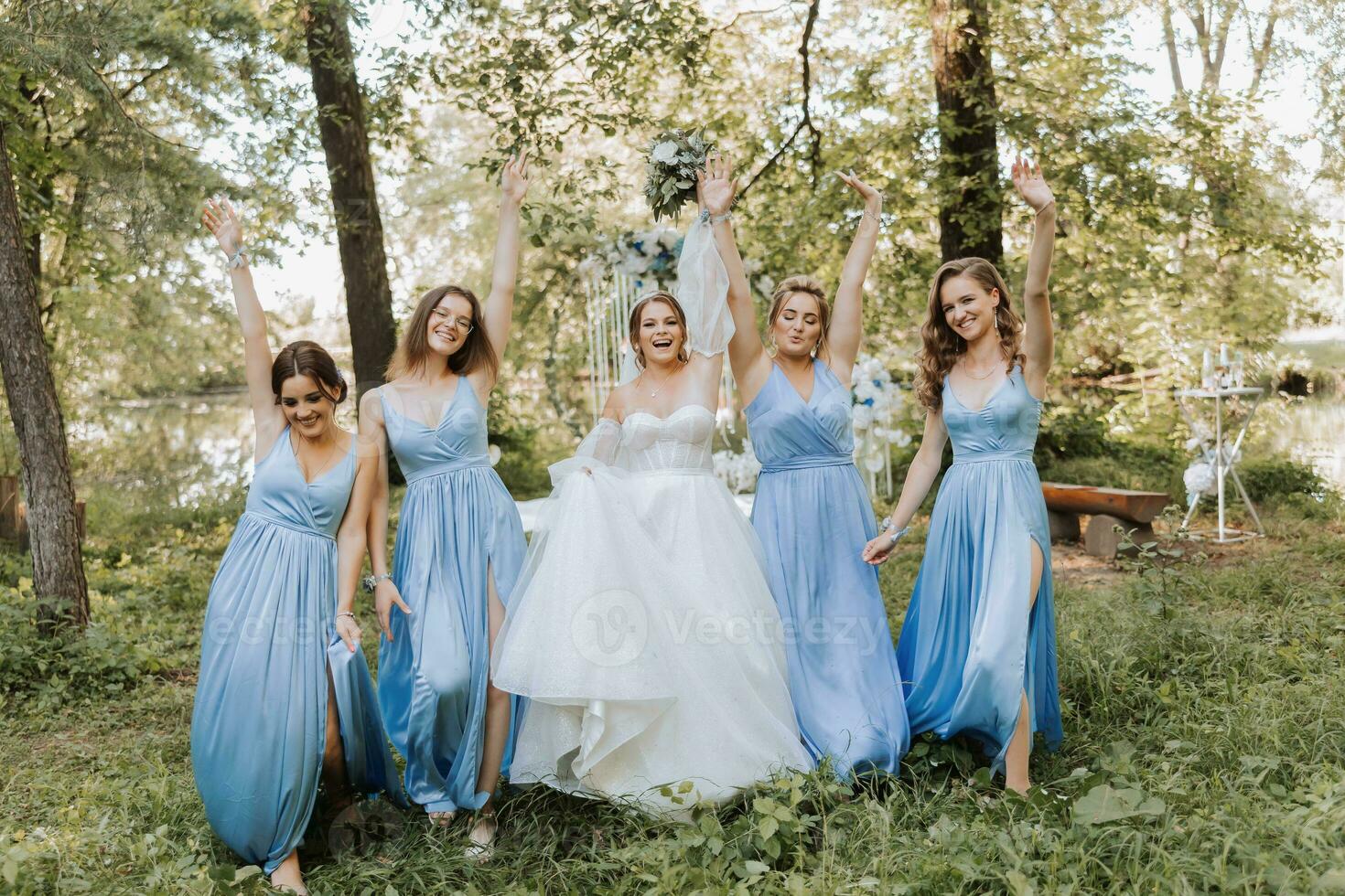 The bridesmaids in blue dresses, the bride is holding a beautiful bouquet. Beautiful luxury wedding blog concept. Spring wedding. photo