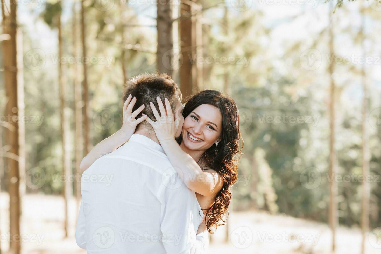 Young happy couple in love hugging smiling and having fun in the mountains. High quality photo. A girl in a beautiful white dress photo
