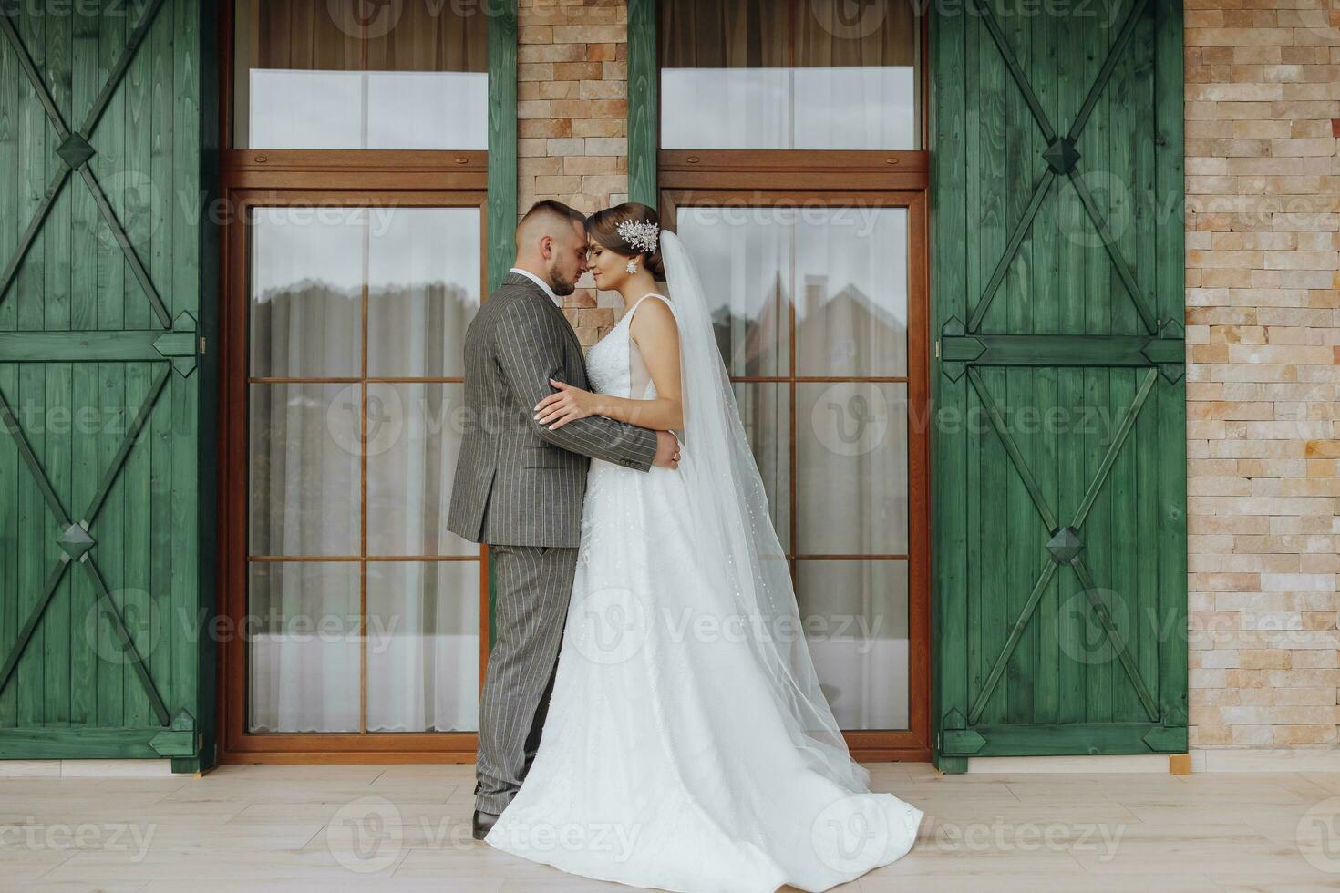 the bride and groom are standing against the background of green windows. Stylish bride and groom. Wedding photo. easy atmosphere photo