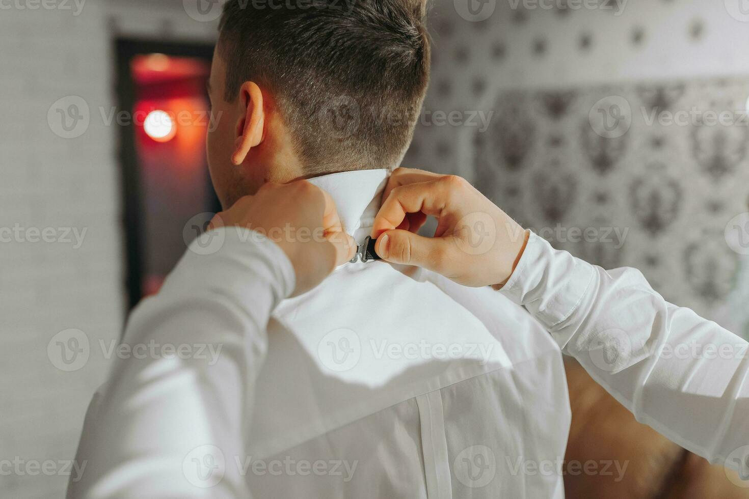 Mañana de el novio y detalles, blanco camisa, bueno luz, joven hombre, elegante novio consiguiendo vestido, consiguiendo Listo para el Boda ceremonia. de cerca de masculino manos, foto