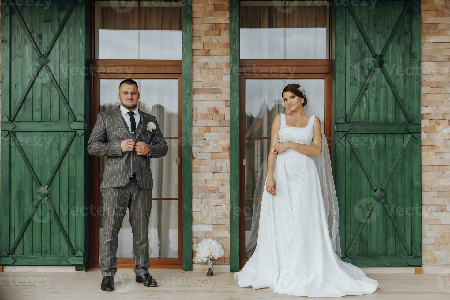 the bride and groom are standing against the background of green windows. Stylish bride and groom. Wedding photo. easy atmosphere photo