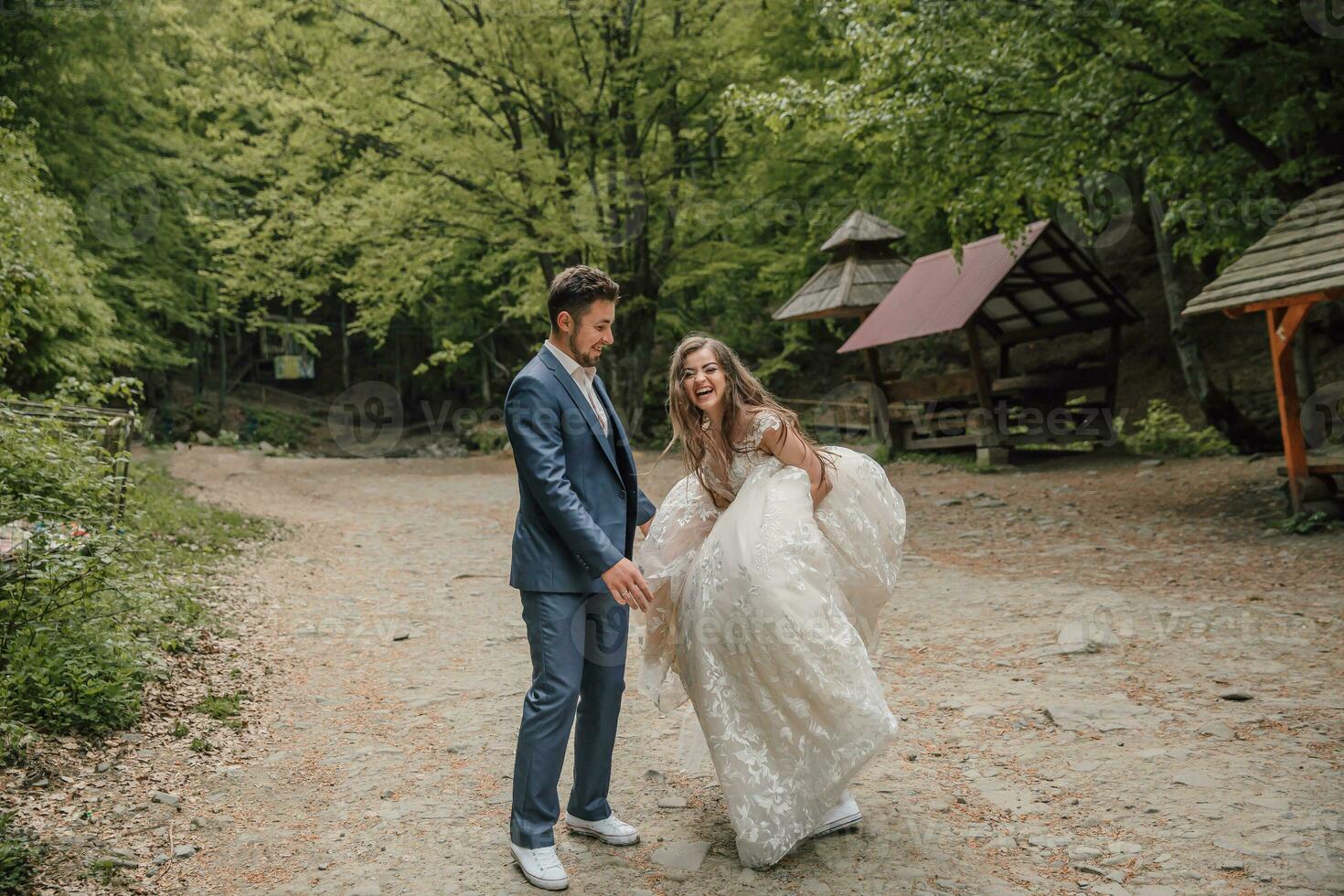 un contento Boda Pareja es corriendo a lo largo un bosque camino. novio y novia. Boda foto sesión en naturaleza. foto sesión en el bosque de el novia y novio.