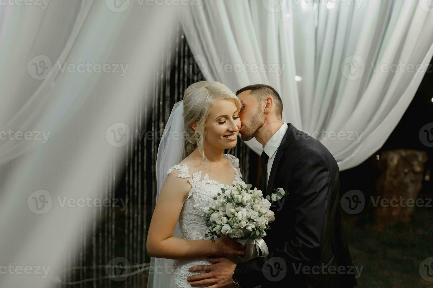 Boda ceremonia en el apuntalar de el lago. pintura ceremonia en el noche. romántico cuadro. el presidio es decorado con blanco flores blanco sillas. el novia y novio suavemente sostener manos foto