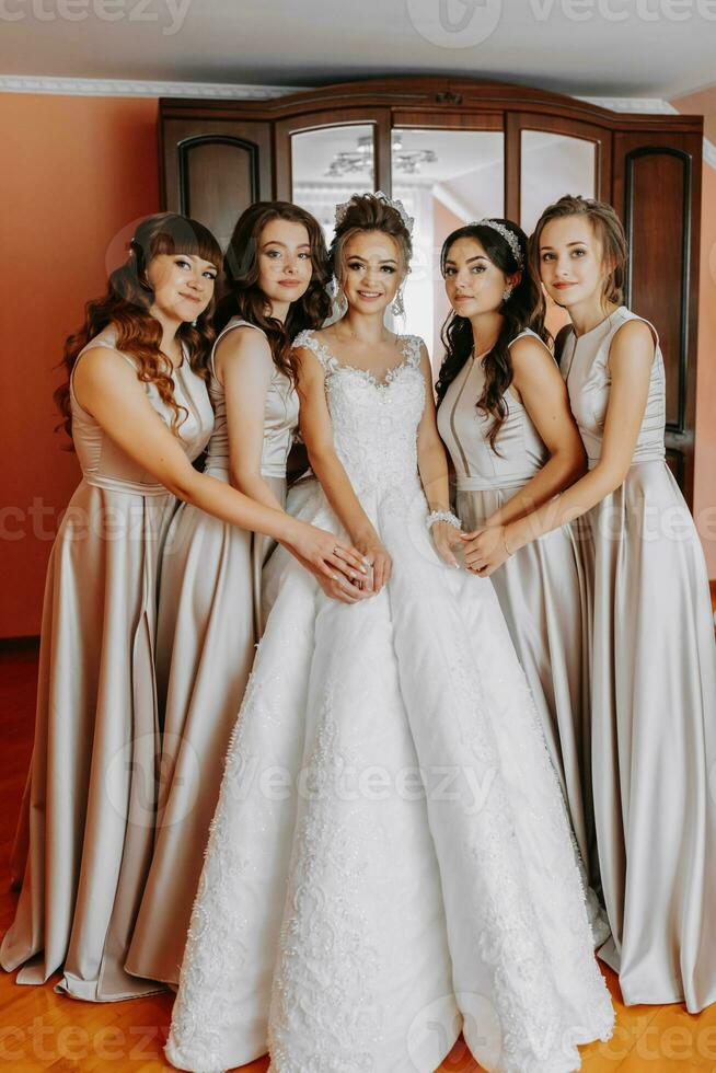 the bride's friend prepares the bride for the wedding day. The bride's friends happily pose with the bride for a photo