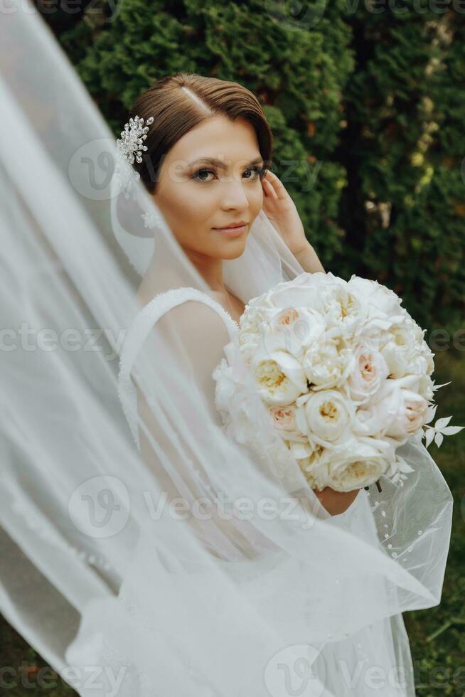 Wedding bouquet of beautiful white wedding flowers in the hands of the bride. outdoor photo in the park. Stylish bride. Delicate make-up