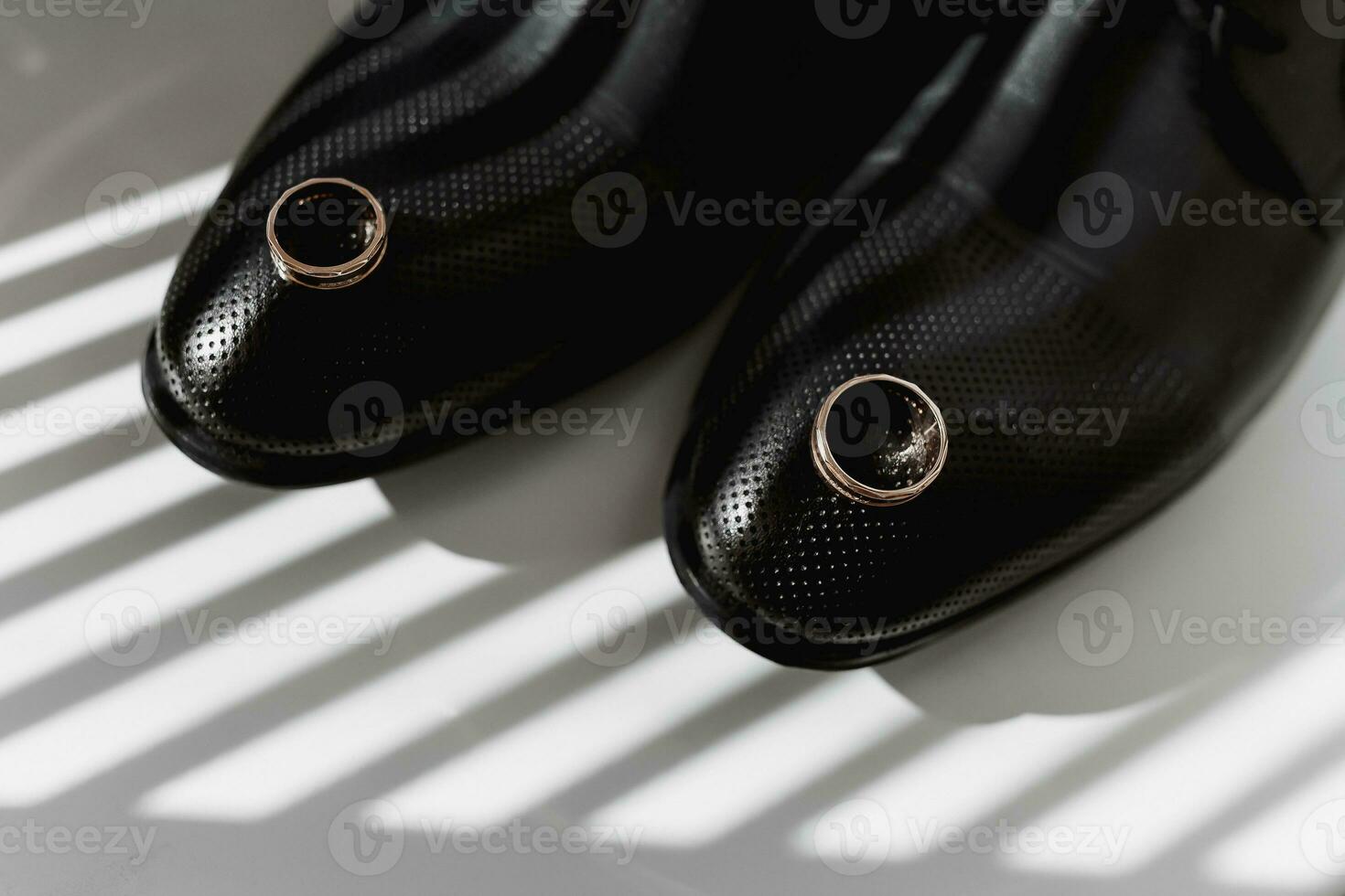 Two golden textured wedding rings on rays of falling light photo