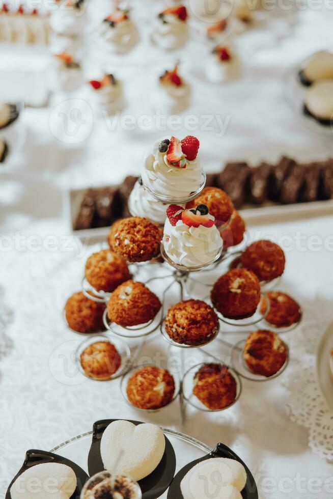 Candy bar. Table with sweets, candies, dessert. cakes and berries in the candy bar. Candy bar with delicious mini cakes, selective focus photo