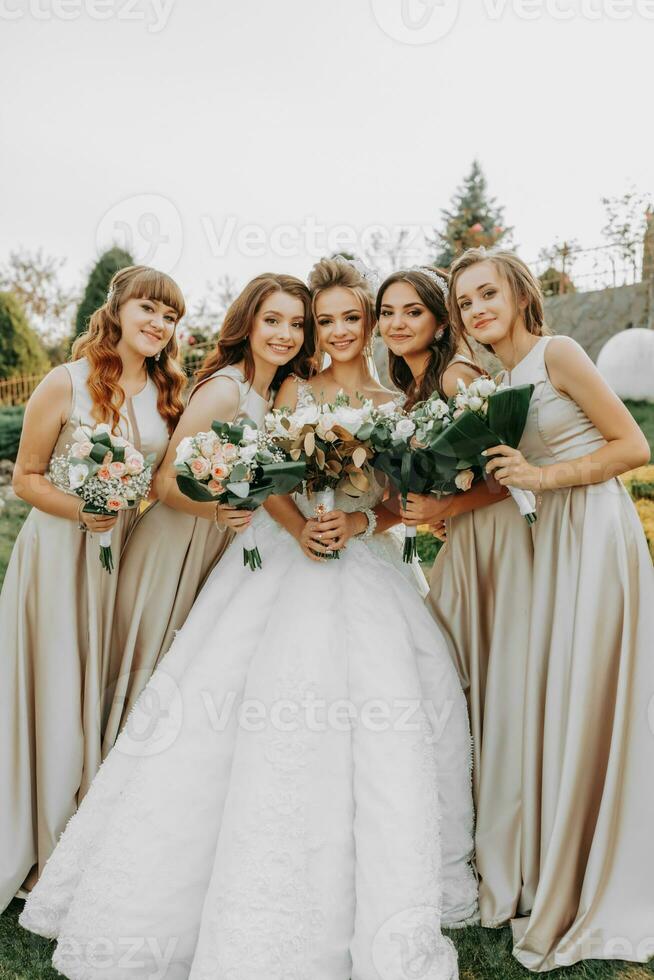 Photo of the bride and bridesmaidswith wedding bouquets. Wedding day. Happy girls at their best friend's wedding. Beautiful bride with her friends. Summer wedding