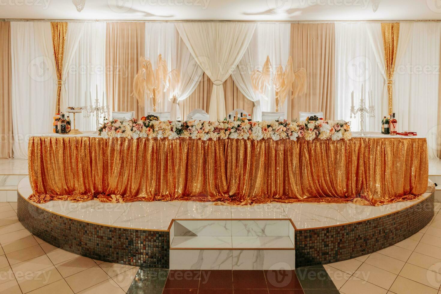 The wedding table of the bride and groom, decorated with flowers, is made in gray color. Candles on stands. Flowers and greenery. Gold. Wedding details photo