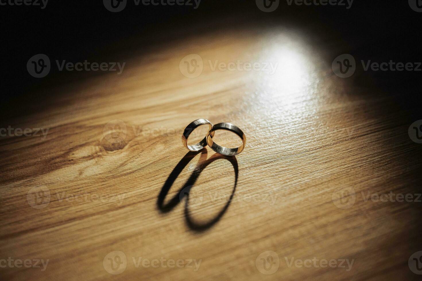 Classic wedding rings on a wood texture background. A beautiful photo with details of the wedding. Wedding day. Contour light. Shadows and light
