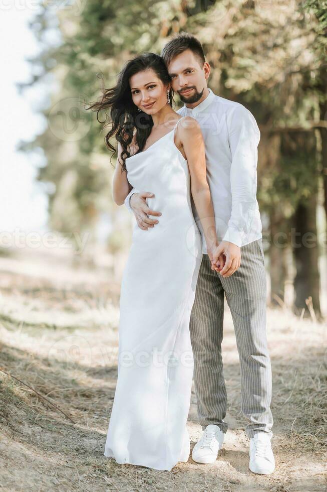 joven contento Pareja en amor abrazando sonriente y teniendo divertido en el montañas. alto calidad foto. un niña en un hermosa blanco vestido. retrato foto