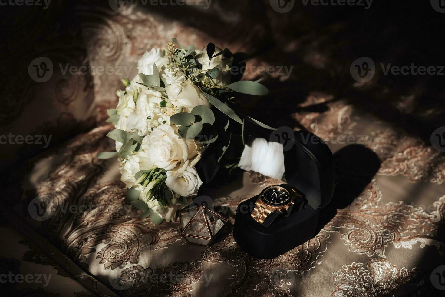 Accessories for the groom's wedding. A bouquet of white roses and greenery stands on the back of the sofa near the window. Beautiful flowers. Light and shadows photo