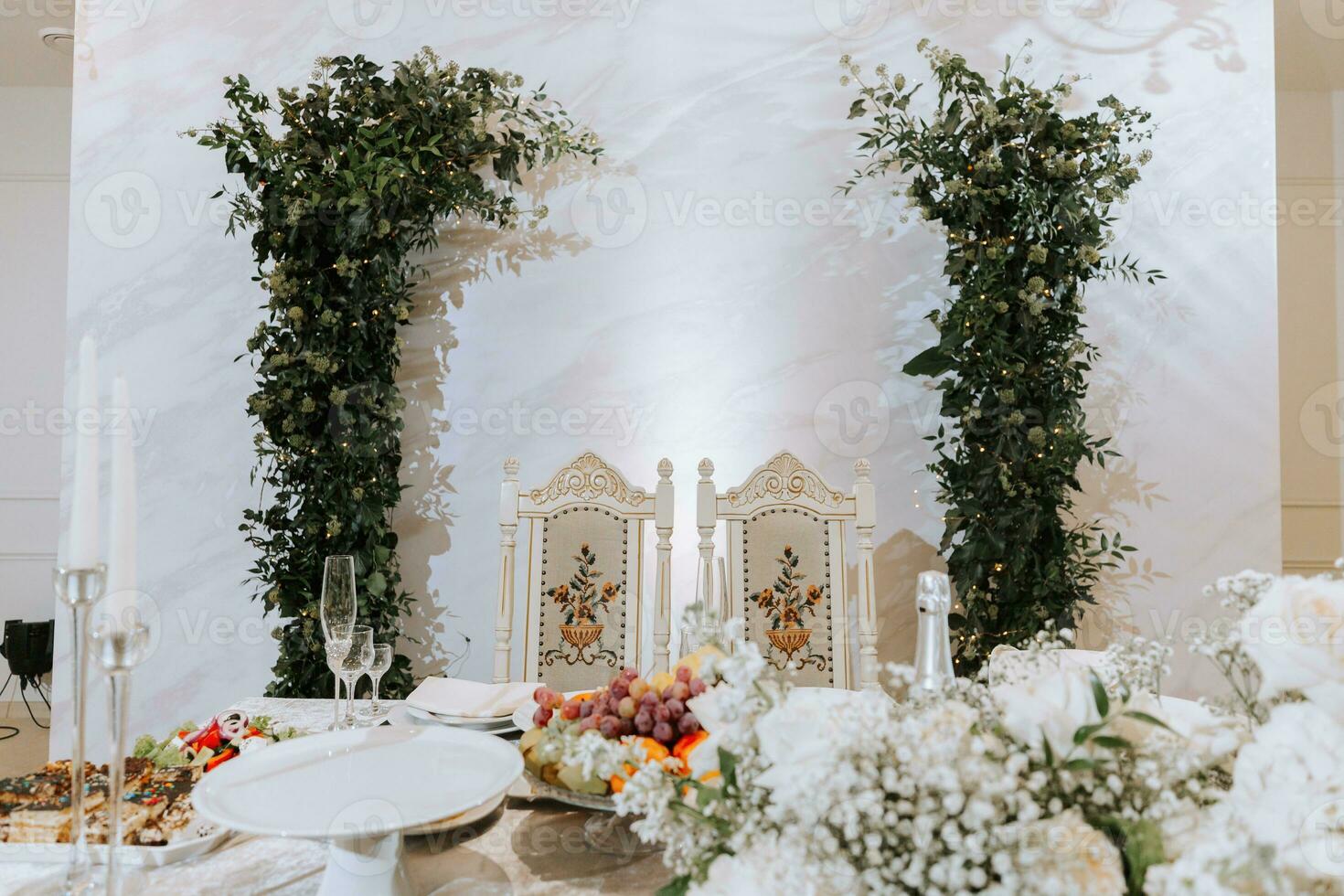 Wedding table serving. Wedding luxury decor. Wedding presidium for the newlyweds. Beautiful decor with pastel roses, candles and greenery. Indoors photo
