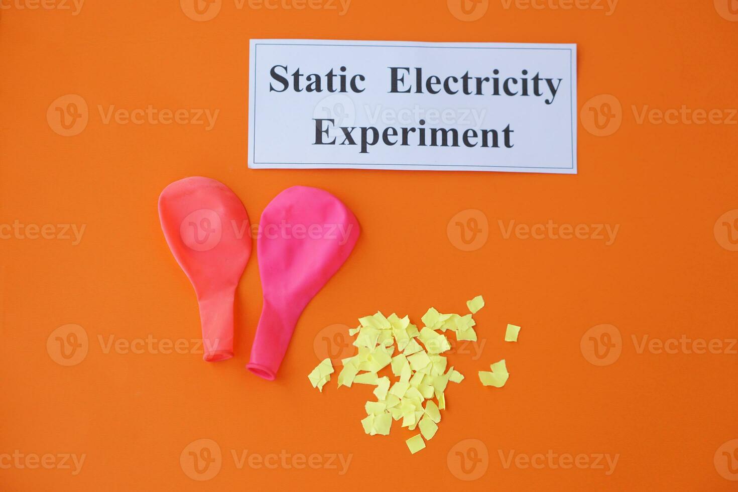 Ballons and small pieces of paper. Equipment, prepared to do experiment about static electricity. Orange background.  Concept, Science lesson, fun and easy experiment. Education. Teaching aids. photo