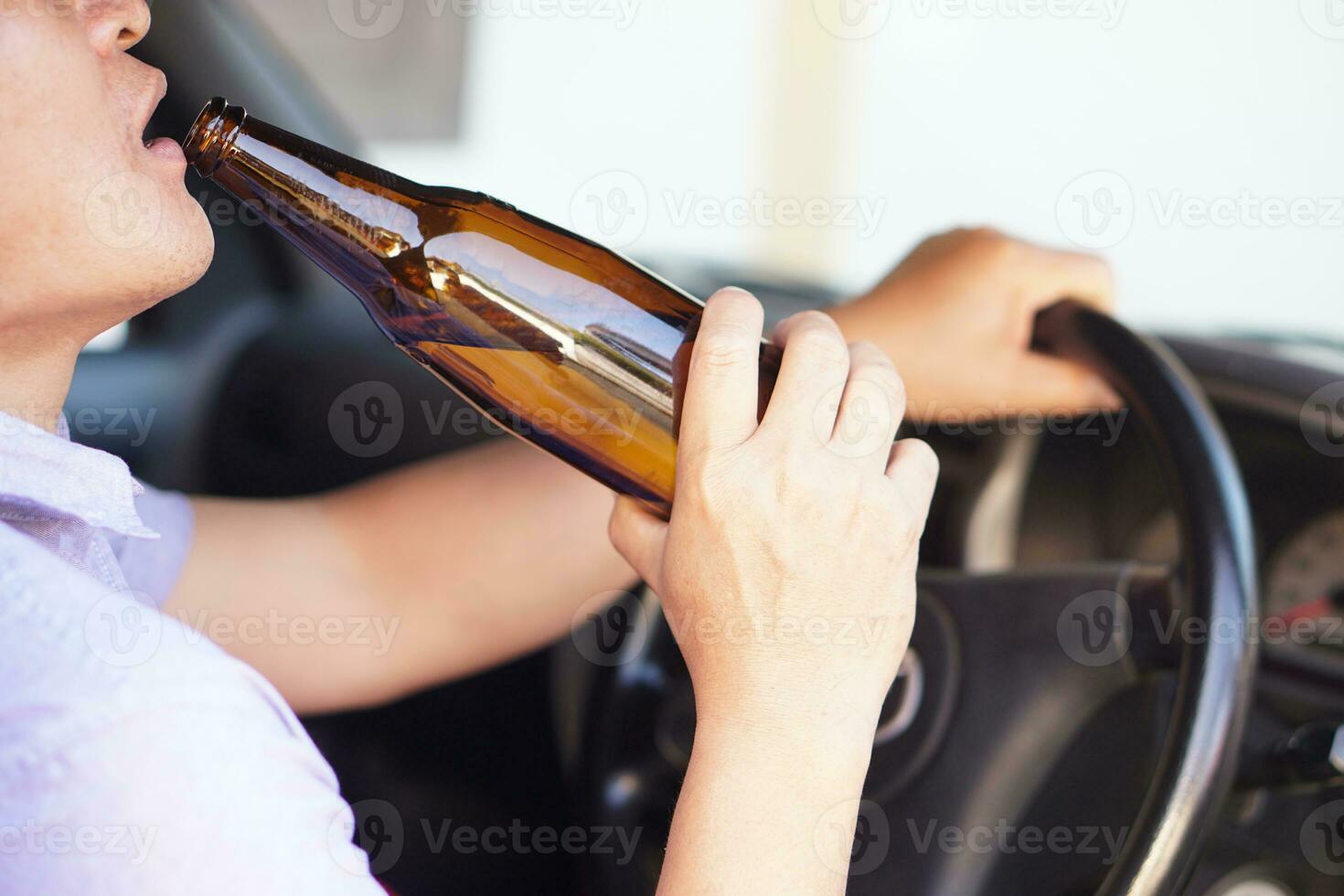 Close up drunk man hold bottle of beer to drink in car. Concept , Campaign for don't drive, don't drink alcohol that can cause car accident and illegal. Dangerous driving when drunk. photo