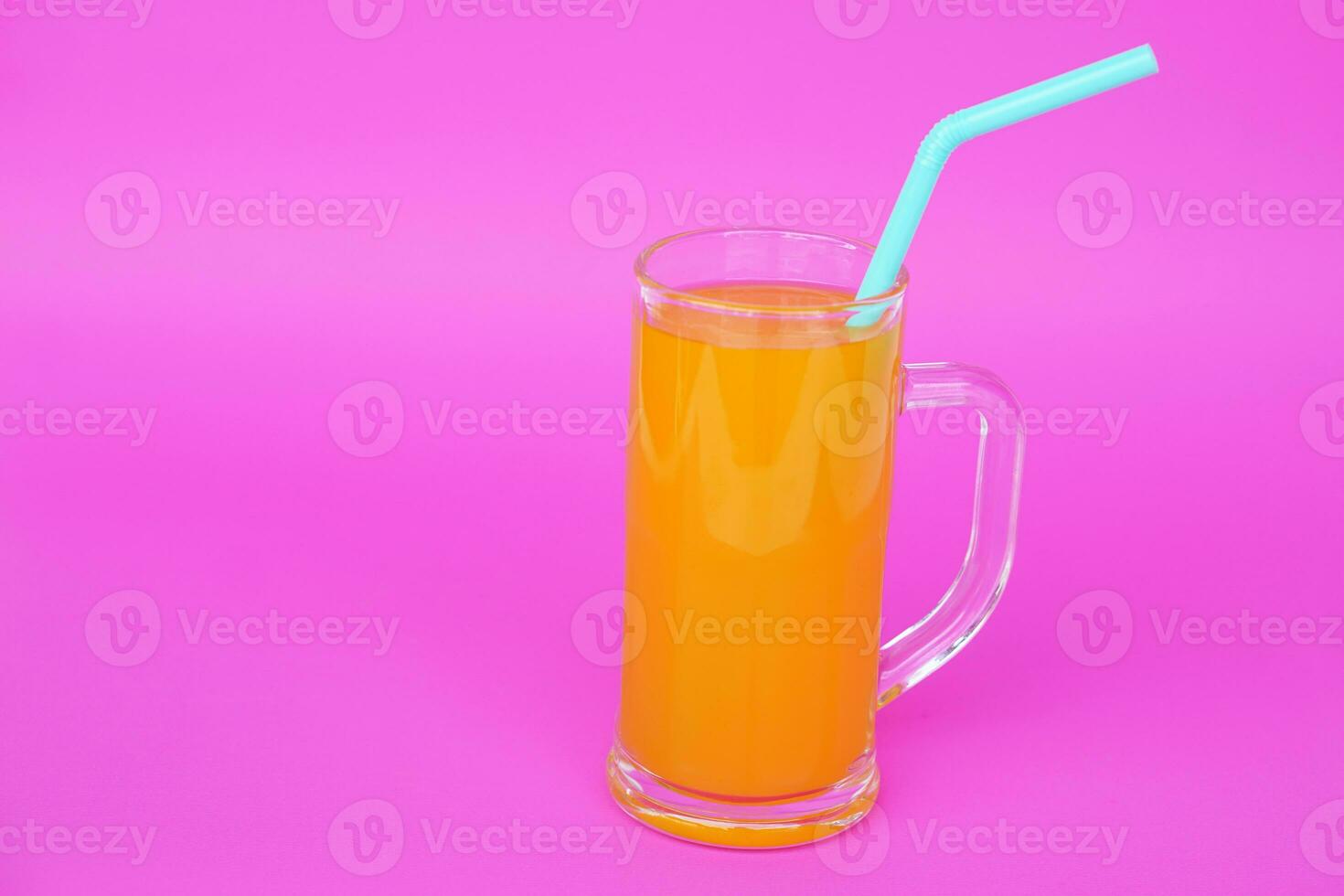 Glass mug of orange juice with drinking straw.  Pink background. Concept, morning refreshing beverage. Sweet, testy and high vitamin C. photo