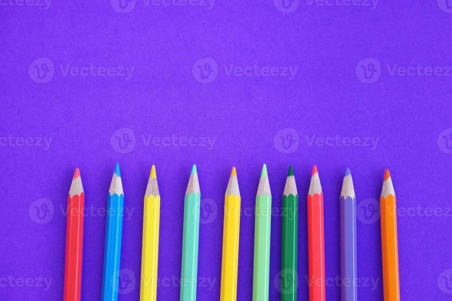 Multi color pencils crayons on purple background with copy space for adding text. Concept, education materials. Art drawing and painting equipment. photo