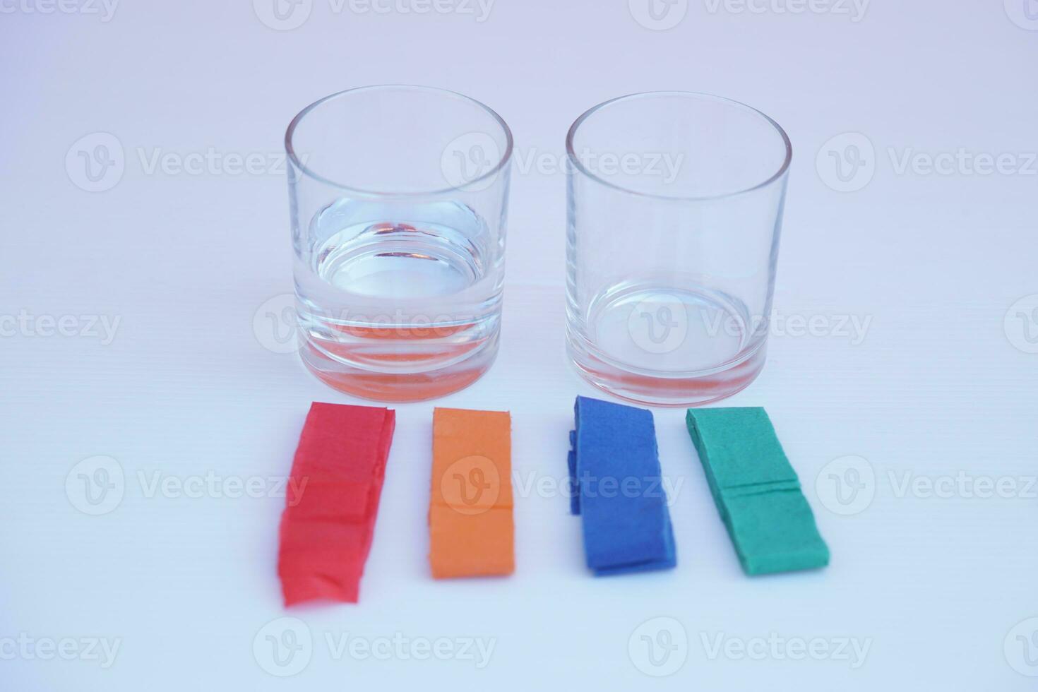 Two glass of water and colorful stripes paper. White background. Equipment prepared for doing science experiment about chromatography. Easy activity chemistry lesson for kid. photo