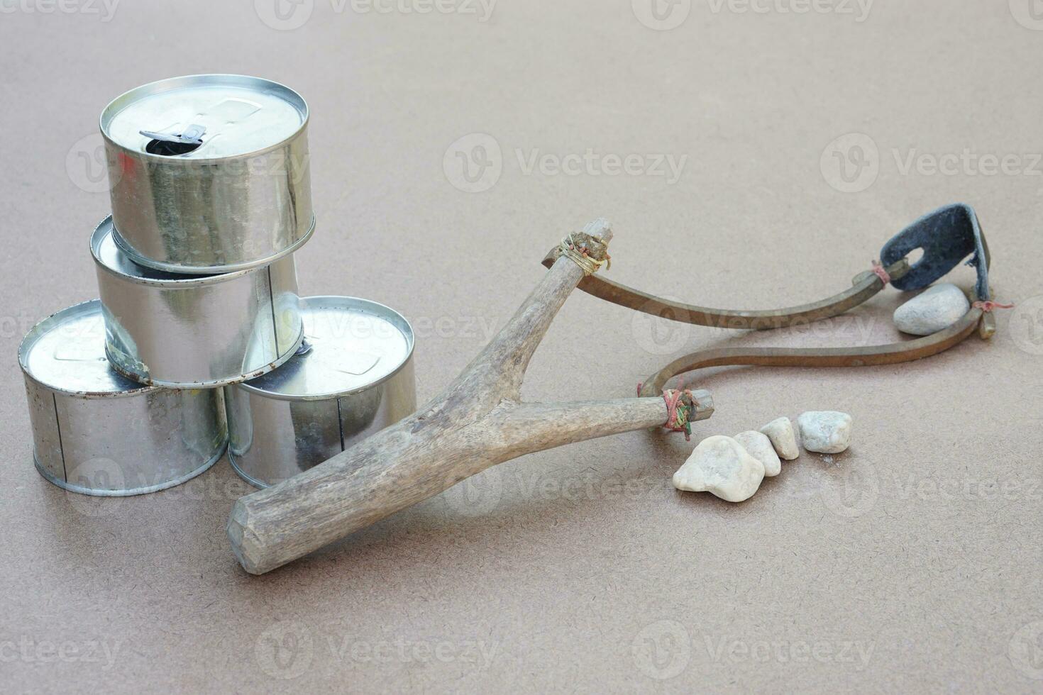 Slingshot, old cans and small rock bullets. Equipments for can shooting game. Concept ,Traditional game, Challenge, aim a catapult with stone bullet to cans and shoot. photo